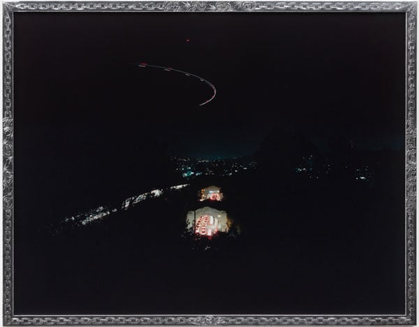 A color photograph shows a view of LA at night, with a tunnel and traffic illuminating a landscape that is an inky black.
