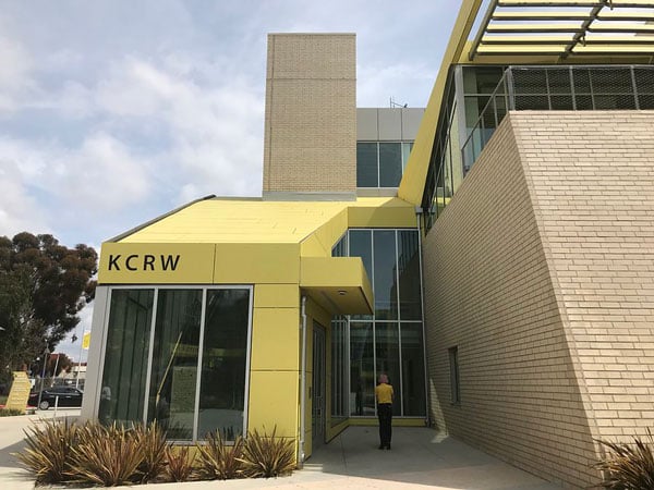 A view of KCRW's Santa Monica headquarters shows a yellow building that bears the KCRW logo