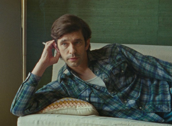 The actor Ben Whishaw, playing Peter Hujar, is seen reclining on a couch while smoking a cigarette in the film "Peter Hujar's Day"