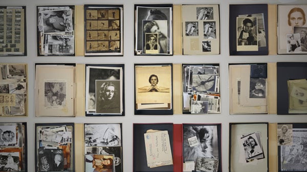 An overhead photo shows files of vintage photos and papers laid out in a tidy grid on a table.
