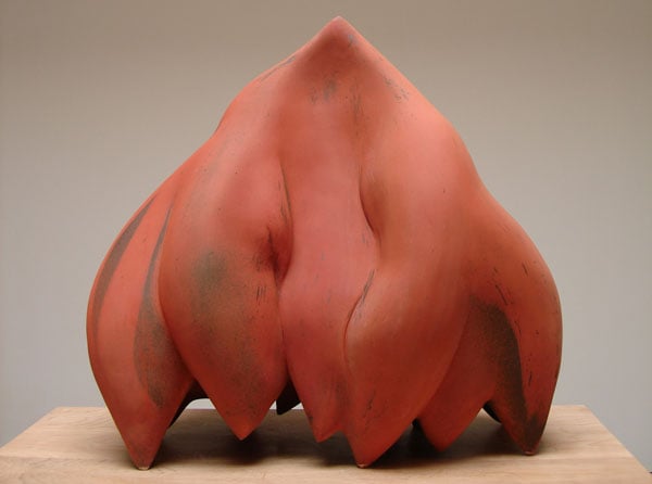 A sculpture by Syd Carpenter made from terracotta-colored clay takes on an abstracted organic form that vaguely echoes a seed pod.