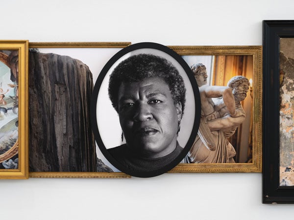 A detail of a photo sculpture by Todd Gray features framed photos arranged atop each other in a collage fashion. At center is a black and white portrait of Octavia Butler.