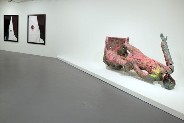 A toppled statue of Jefferson Davis splattered in pink paint lays before images of KKK members.