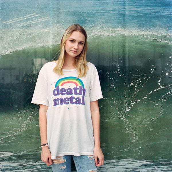 A color photo by Deanna Templeton shows a teen girl wearing a t-shirt with a rainbow that reads "Death metal" before an image of a wave.