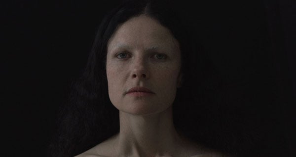 A film still shows a close-up on an attractive brown-haired White woman with freckles.