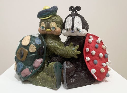 A ceramic shows cartoonish depictions of a turtle and a ladybug hugging.