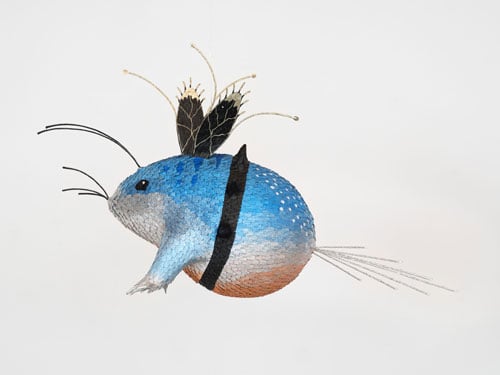A brilliant blue piñata in a gallery features a hybrid mouse-like creature with wings.