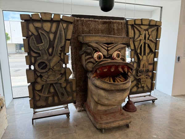 A sculpture in a gallery shows a toilet with bulging eyes and large teeth