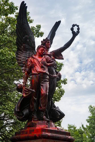 A Confederate bronze stnding in a plaza is splattered in red paint.