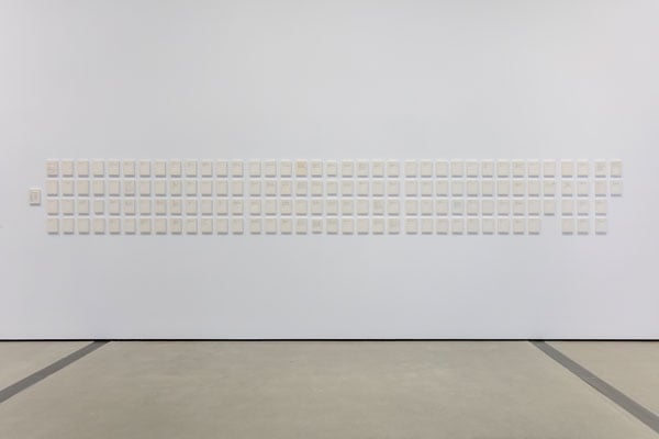 A gallery wall displays 151 framed, cream-colored cards that on their surface contains short, type written instructions that are barely visible in this image.