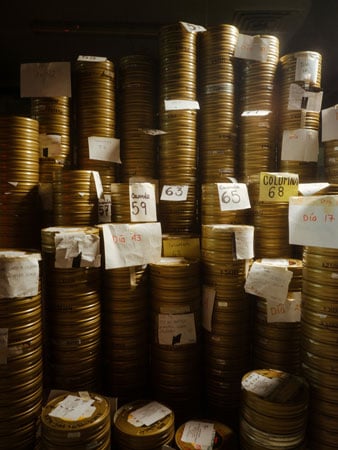 A room is stuffed with piles and piles of celluloid film reels in tins.