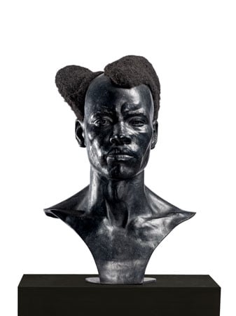 A bronze bust of a Black man features a stylish asymetrical hairdo made with real hair.