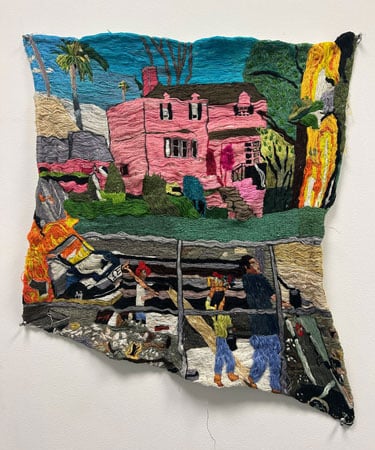 An embroidered tapestry shows a pink house. To one side are flames, in the foreground are workers.