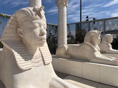 A row of three gleaming sphinxes bearing the stoic faces of Black people sit in a row in Lauren Halsey's "sister dreamer" park
