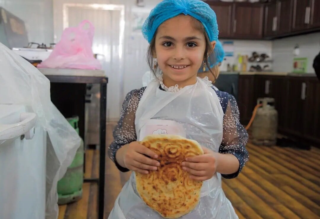 A young girl holds Eid bread that is made with a wooden mold and eaten during Ramadan. Photo by Alex Lau.