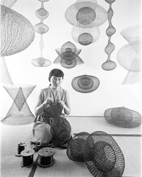 A Japanese American woman is shown creating looped wire sculptures in a vintage image from the '50s.