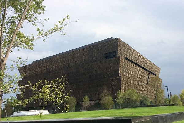 A side view of the NHMAAC shows its inverted ziggurate form and metallic lattice facade.