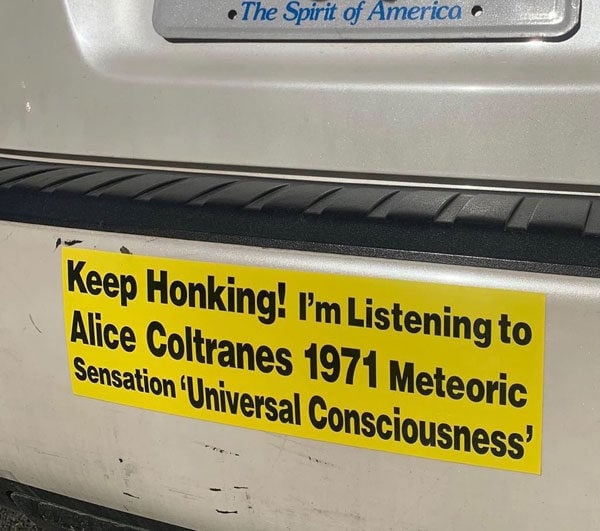 A yellow bumper sticker reads, "Keep Honking I'm Listening to Alice Coltrane's 1971 Meteoric Sensation 'Universal Consciousness'"