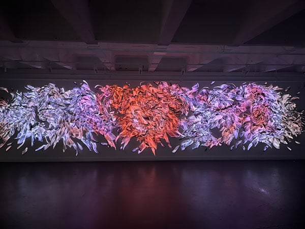 Red and purple light are projected on a sculpture of cut paper by Nancy Baker Cahill