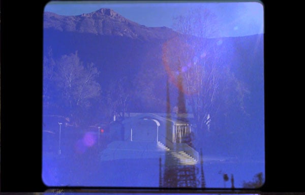 A still shows a cross fade between an ashram and the Watts Towers