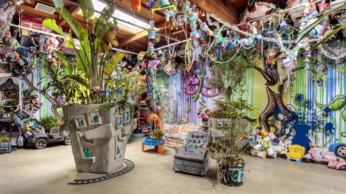 Kenny Scharf, SUNSHINE CAVERN, 2024. Found objects, concrete planters, jungle, disco ball, found object garlands, tinsel, spray painted couches, and spray paint on canvas. Image courtesy of Honor Fraser Gallery. Photo: JW Pictures. 