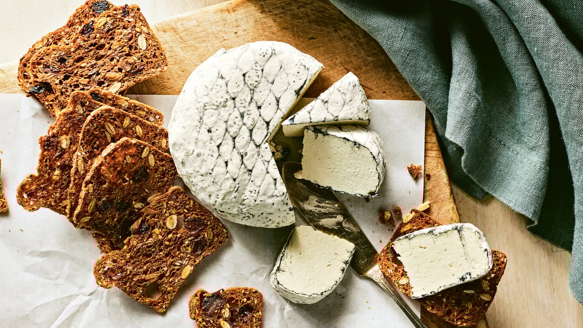 a round of vegan cheese next to crackers