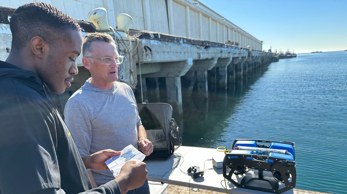 AltaSea’s Alan Hill (right) teaches Ernest Ekejiuba (left), a senior at King/Drew Magnet High School, how to operate a professional grade underwater robot. Photo by Zeke Reed.
